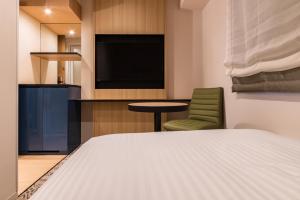 um quarto com uma cama, uma televisão e uma cadeira em Hotel Vista Fukuoka Nakasu-Kawabata em Fukuoka