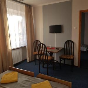 a hotel room with a table and chairs and a television at Pensjonat MALWA in Brenna