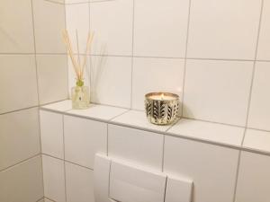 a white tiled bathroom with two vases on a shelf at Apartment Marktplatz in Basel