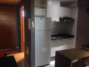 a kitchen with a white refrigerator and a table at Estudio West Flat Mossoró in Mossoró