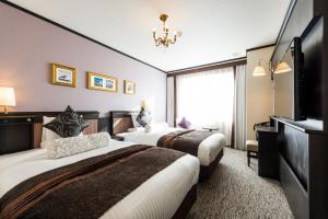 ein Hotelzimmer mit 2 Betten und einem TV in der Unterkunft Hotel Sonia Otaru in Otaru