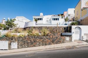 a stone wall next to a street with houses at Sea view villa San Agustin vista Claveles in San Agustin