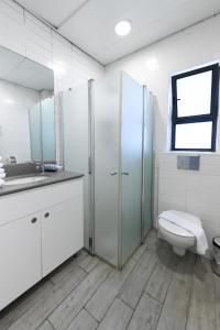 a white bathroom with a toilet and a sink at HI - Bnei Dan - Tel Aviv Hostel in Tel Aviv