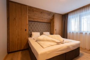 een slaapkamer met een groot bed met een houten hoofdeinde bij A CASA Aquamarin in Sölden