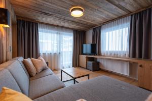 een woonkamer met een bank en een tv bij A CASA Aquamarin in Sölden
