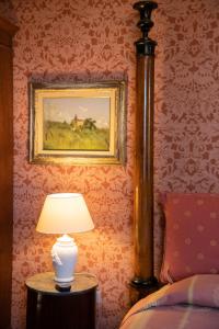 una lámpara en una mesa junto a una cama en Villa Pedone, en Lucca