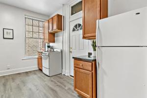 La cuisine est équipée d'un réfrigérateur blanc et de placards en bois. dans l'établissement Cool 2BR Apartment close to Fun City - Grace 2, à Chicago