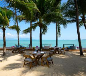a beach area with tables, chairs and umbrellas at Samui Palm Beach Resort - SHA Extra Plus in Bophut