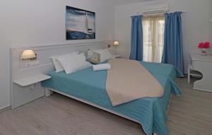 a bedroom with a bed with blue sheets and a window at Angela Beach Apartments in Votsalákia