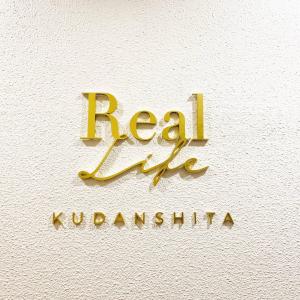 Złoty znak z napisem "prawdziwa kuwaititution" na ścianie w obiekcie Real Life Kudanshita w Tokio