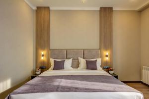 a bedroom with a large bed with purple pillows at Sara Boutique Hotel in Bishkek