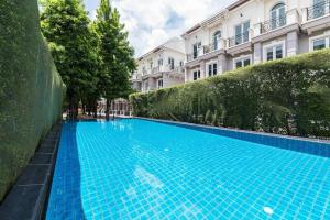 une grande piscine bleue en face d'un bâtiment dans l'établissement MIQ Asoke202 Pool Villa - Asoke BTS 16 Pax, à Bangkok