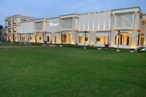 a large building with a large green field in front of it at Mayur Hotel & Resort in Sītāpur