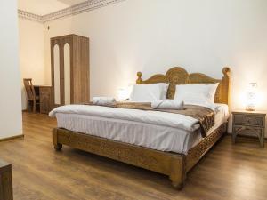 a bedroom with a large bed with a wooden headboard at Royal Bukhara hotel in Bukhara