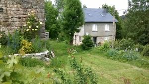 einen Garten vor einem Steinhaus in der Unterkunft Au Domaine des oiseaux in Montredon