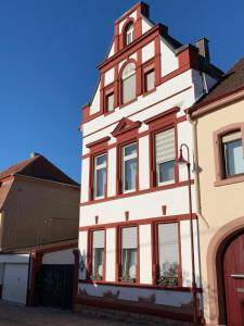 a tall white building with red accents at Ferienwohnung Vino Palatina in Maikammer