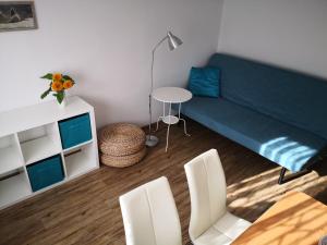 uma sala de estar com um sofá azul e cadeiras brancas em Apartmán 577 em Cesky Krumlov