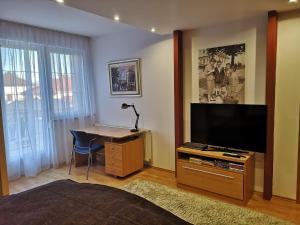 a bedroom with a tv and a desk with a lamp at Hotello Apartmanház és Panzió in Zalaegerszeg
