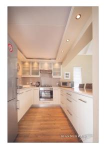 a kitchen with white cabinets and a wooden floor at Bruckendorf Self Catering Apartment in Swakopmund