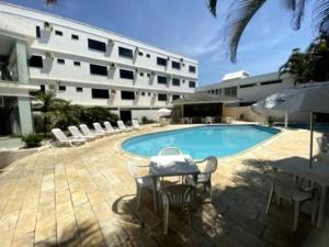 a swimming pool with a table and chairs and a building at Scaini Palace Hotel in Arroio do Silva