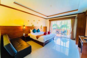 a bedroom with a bed and a couch and a window at Peaceful Resort , Long Beach - Koh Lanta in Ko Lanta