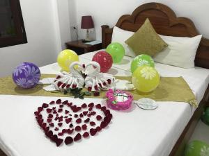 a bed with balloons and a heart shaped cake on it at Elephant Boutique Hotel in Luang Prabang