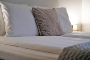 un letto con lenzuola bianche, cuscini e un cuscino di Krak Apartments a Cracovia