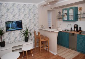 a kitchen with blue cabinets and a tv on the wall at Apartment - Aloha - Parter - Self check 24h in Bytom