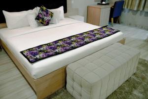a large bed with a bench in a room at Visa Karena Hotels in Port Harcourt