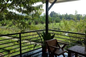 a room with a balcony with a view of a field at Rai Boonsom in Phrao