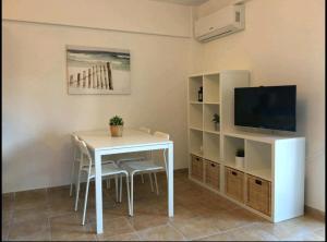 ein Wohnzimmer mit einem weißen Tisch und einem TV in der Unterkunft Acogedor apartamento junto al mar in Las Negras
