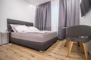 um pequeno quarto com uma cama e uma cadeira em Main Square Modern Apartments em Zagreb