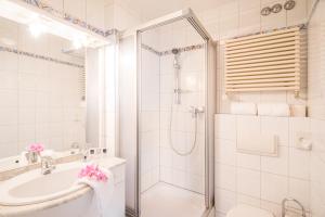 a white bathroom with a shower and a sink at Hotel Buschhausen in Aachen