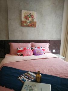 Schlafzimmer mit einem Bett mit rosa Bettwäsche und Kissen in der Unterkunft Your Perfect Stay for Shopping and Entertainment - Hostahome Suites at I-City in Shah Alam