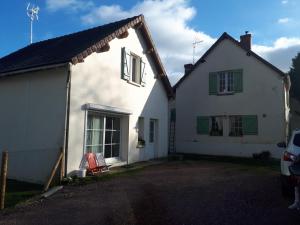 ein weißes Haus mit einem roten Stuhl davor in der Unterkunft Bienvenue chez les GIBBS! in Sury-en-Vaux
