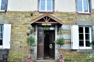 La Maison du Chene في Percy: مبنى من الطوب مع باب خشبي ونوافذ