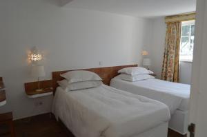 Hotel Vasco Da Gama في مونت غوردو: سريرين في غرفة ذات أغطية ووسائد بيضاء