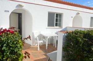 Dieses weiße Haus verfügt über eine Terrasse mit einem weißen Tisch und Stühlen. in der Unterkunft Hotel Vasco Da Gama in Monte Gordo
