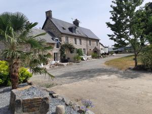 une vieille maison avec un palmier en face dans l'établissement Bijoux Gite, à Argouges