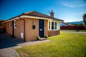 a small brick house with a blue door at Silverglades Holiday Homes in Aviemore +126 photos