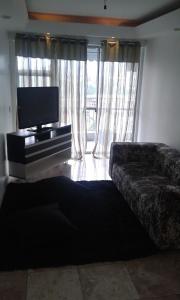 sala de estar con TV de pantalla plana y sofá en Barra da Tijuca, en Río de Janeiro