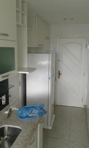 a kitchen with a white refrigerator and a door at Barra da Tijuca in Rio de Janeiro