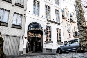 una tienda frente a un edificio blanco con un coche aparcado fuera en The Pand Hotel - Small Luxury Hotels of the World, en Brujas