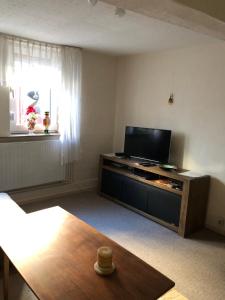 a living room with a flat screen tv on a entertainment center at Ferienwohnung beim Dünzebacher Torturm in Eschwege