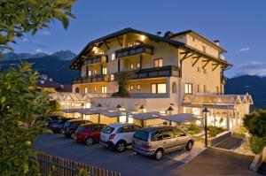 a large building with cars parked in a parking lot at Alpentirolis in Tirolo