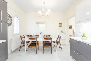 a white kitchen with a dining room table and chairs at Lux 3-bedroom Villa - L&L Refuge in Nea Makri