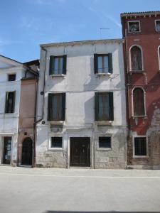 a white building with green shutters on a street at Casa Renata in Venice