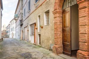 eine Gasse mit einem alten Gebäude und einer Holztür in der Unterkunft La Rocca in Sinalunga