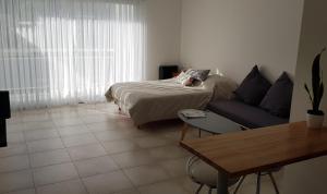 1 dormitorio con cama, sofá y mesa en Depto nuevo, luminoso, excelente ubicación, ideal para descansar. en Mar del Plata