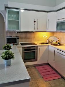cocina con armarios blancos y alfombra roja en Potamos apartment with view en Potamós